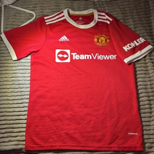 Manchester United tröja  - Röd Manchester United fotbollströja från Adidas med vita detaljer och klubbmärke på bröstet. Har använts två gånger, eftersom jag har vuxit ur den.  Pris går ej att förhandla, billigt.