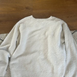 Vit fluffig stickad tröja! - Supermjuk och fluffig vit stickad tröja med lång ärm och rund hals. Perfekt för kyliga dagar när du vill ha något riktigt mysigt och varmt!