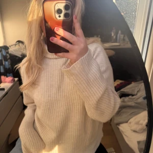 Beige ribbad polotröja från H&M - Supermysig beige polotröja från H&M i ribbstickat material. Tröjan har lång ärm, hög krage och en loose fit som ger en chill vibe. Perfekt att styla med jeans eller kjol för en enkel men snygg look.