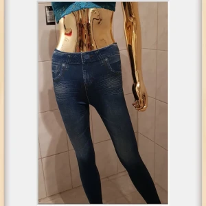 Mörkblå leggings S/M - Supersköna "fodrade" mörkblå leggingsjeans från JeanEez med jeanslook och tryckta fickor. Tight passform, tillverkade i stretchigt material med 95% polyester och 5% elastan. Perfekta för en avslappnad och trendig stil.