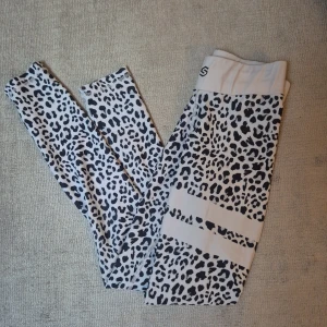 Leopardmönstrade leggings från Stronger - Snygga leggings från Stronger i vitt och svart leopardmönster. Hög midja och stretchigt material i polyester och elastan gör dem perfekta för träning eller chill.