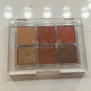 CAIA Heat Wave ögonskuggspalett - Snygg ögonskuggspalett från CAIA med sex nyanser: Tan, Flames, Spicy, Lava, Hotter och Desert. Färgerna går i varma toner av guld, brons, koppar och brunt. Paletten har både matta och skimriga skuggor i ett smidigt plastetui.
