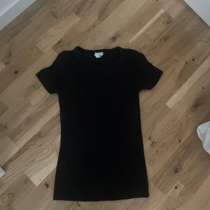 Svart basic t-shirt - Enkel svart t-shirt med rund hals och korta ärmar. Modellen är rak och passar perfekt till jeans eller shorts. T-shirten är stilren och funkar till det mesta, ett måste i garderoben.