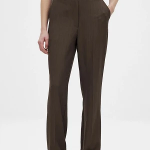Bruna kostymbyxor från NA-KD - Eleganta, mörkbruna byxor med hög midja och raka ben. Byxorna har en klassisk design med pressveck och fickor.  Helt ny!  Storlek: 40  Pris: 160 kr