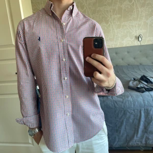 Rutig skjorta från Ralph Lauren S - Säljer en klassisk rutig skjorta från Ralph Lauren i custom fit. Skjortan har röda, blå och vita rutor, button down-krage och broderad logga på bröstet. Tillverkad i mjuk bomull och har långa ärmar med knappar vid manschetterna. Perfekt för en clean och stilren look. Den är nästan nytt skick. Passar en som är emellan 170-180. Priset går såklart att diskuteras! 
