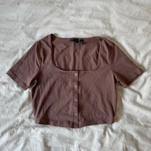 Brun topp med knappar - En brun topp från ASOS med korta ärmar, fyrkantig urringning och knappar framtill. Jättefint skick!