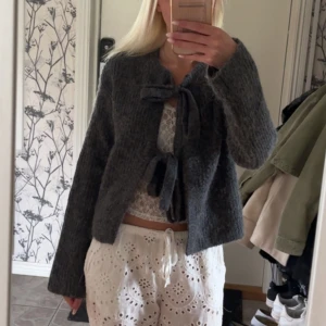 Grå kofta - Mysig grå kofta från Gina Tricot i stickat material. Koftan har långa ärmar och knyt framtill som ger en söt touch. Perfekt att slänga över en topp för en chill och trendig look🤗💕💕Använd 1-3 gånger, så inga tecken på användning!