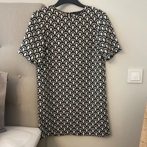 Svartvit mönstrad klänning Zara Woman - Kort klänning från Zara Woman i svartvitt grafiskt mönster. Modellen är rak med rund halsringning och korta ärmar. Tunt, mjukt tyg som känns skönt mot huden. Perfekt för dig som gillar en stilren men ändå unik look. Styla denna fina klänning med ett snyggt skärp är en riktig fin outfit👌🏻Klänningen är i mycket bra skick och pris går att diskuteras!👗