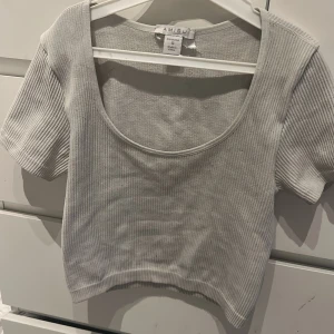 Vit  ribbad croppad topp Amisu - Superfin vit croppad topp från Amisu med ribbad struktur. Toppen har korta ärmar och en djup rundad urringning framtill. Perfekt att matcha med höga jeans eller kjol för en clean och enkel look.  Obs, tröjan är ganska croppad! Skriv om bild behövs på☺️