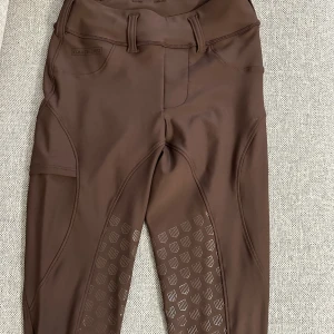 Bruna ridleggings från Maya Delorez XS - Snygga bruna ridleggings från Maya Delorez i storlek XS. De har hög midja, bälteshällor, praktiska fickor och silikonprint på benen för extra grepp. Tillverkade i stretchigt syntetmaterial som är perfekt för ridning. Orginalpris: 1 199kr, priset kan diskuteras vid snabbaffär. Säljer fler ridbyxor.