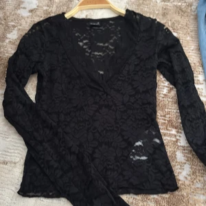 Svart spetsblus från Gina Tricot XS - Supersnygg svart blus i spets från Gina Tricot. Blusen har lång ärm, v-ringning och ett blommigt spetsmönster, använd ett fåtal gånger och är i storlek xs