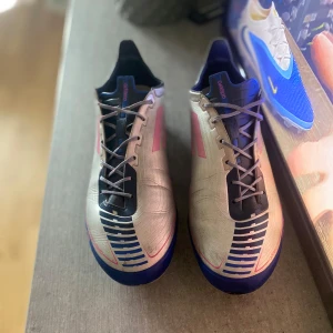 ADIDAS F50 ADIDAS F50 GHOSTED FG UCL - SILVER/ROSA/NAVY LIMITED EDITION - SILVER/ROSA/NAVY LIMITED EDITION - Säljer ett par Adidas F50 ghosted FG UCL limited edition. Fotbollsskor i silver med rosa och mörkblåa detaljer och kolfiber sula för en snabbare respons i din acceleration. Skorna har snörning som är från en annan sko pga att den förra gick sönder under en stämpling, klassisk låg profil och är tillverkade i syntetmaterial för lätt känsla på planen. Perfekta för dig som vill sticka ut med stilrena och snabba skor. Jag har även bytt ut sulan till en ny från en nyare f50 sko för en bättre kännsla.
