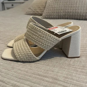Beige sandaler med flätade band och klack - Snygga sandaler från H&M i beige med två breda flätade band och fyrkantig tå. Aldrig använda 