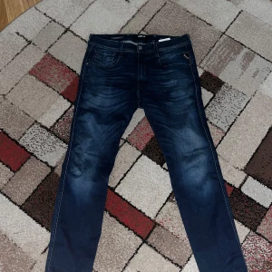 Replay Hyperflex jeans blå 32/30 - Snygga Replay Hyperflex jeans i mörkblå tvätt med klassisk femficksdesign och diskreta slitningar. Stretchigt material som ger skön passform och rörelsefrihet. Perfekt för dig som vill ha stilrena jeans med modern känsla och coola detaljer.