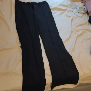 Svarta byxor med raka ben - Snygga svarta byxor med pressveck och raka ben. Klassisk modell med midjehällor och diskret dragkedja framtill. Perfekta för en clean och stilren look.