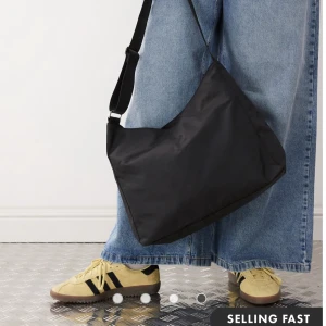 Svart axelväska från Weekday - Stor svart axelväska från Weekday med justerbart band. Väskan har en enkel och clean design i syntetmaterial, perfekt för att bära allt du behöver till skolan eller stan. Rymmer mycket och är lätt att matcha med olika outfits. Kostar 499kr ny