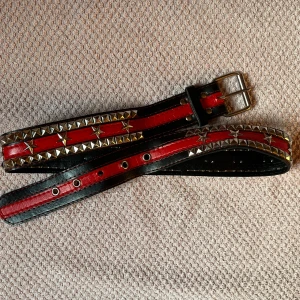 Nitbälte - Coolt svart och rött bälte med nitar. Är i bra skick och är 100cm långt.