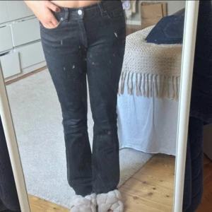 Svarta bootcut jeans - Säljer ett par svarta jeans med bootcut-modell och klassisk femficksdesign. Jeansen har hög midja och är tillverkade i ett stretchigt denimtyg som sitter snyggt över höfterna och släpper ut vid bensluten.