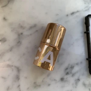 CAIA highlighter stick champagne - Säljer en CAIA highlighter stick i en snygg champagnefärgad ton. Kommer i en lyxig guldig hylsa med vit logga och har en krämig formula som ger glow till kindben, näsa eller ögonbryn. Perfekt att applicera direkt från sticket för en fräsch och glansig finish.