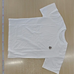 Vit t-shirt från Moncler - Vit t-shirt från Moncler med klassisk rund hals och korta ärmar. T-shirten har en liten broderad Moncler-logga på bröstet och är gjord i mjuk bomull. Perfekt för en clean och stilren look.