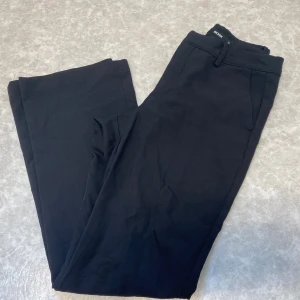 Svarta kostymbyxor från Bik Bok - Svarta kostymbyxor från Bik Bok med klassisk rak passform. Byxorna har hällor för bälte, snedställda fickor fram och dekorativa fickor bak. Perfekta för en clean och stilren look. Materialet känns mjukt och följsamt.