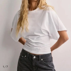 Vit snygg t-shirt - Vit snygg topp med tajt midja och lösare upp till från Nelly i storlek S, endast använd 1-2 ggr