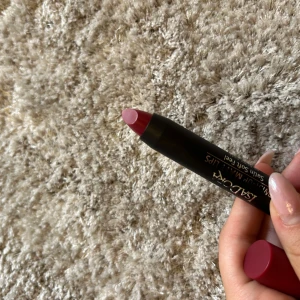 Isadora Twist-Up Matt Lips Ruby Gem - Matt läppstift från Isadora i färgen 65 Ruby Gem. Pennformat med twist-up funktion och satin soft feel. Färgen är en djup rubinröd med matt finish, perfekt för att ge läpparna ett snyggt statement. Hylsan är svart med vinröd kork och detaljer i guld.