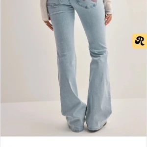 Ljusblå bootcut jeans med slitningar - Snygga ljusblå jeans med bootcut passform och slitna hål över knäna. Jeansen har klassisk femficksdesign och är tillverkade i mjukt denimtyg. Perfekta för en avslappnad och trendig look.