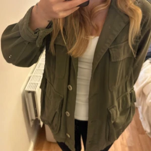 Grön jacka från Zara - Snygg olivgrön overshirt med fyra stora fickor framtill och knäppning med knappar. Jackan har en avslappnad passform, perfekt att slänga över en hoodie eller t-shirt. Långa ärmar som kan vikas upp för en chill look.