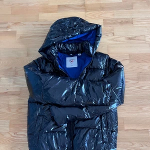 Svart pufferjacka från Rossignol - Säljer en glansig svart pufferjacka från Rossignol. Jackan har dragkedja framtill och är riktigt varm och skön. Använd ett fåtal gånger och har inga tecken på slitage. Inköpt förra vintern. Normal i storleken (strl 16, motsvarar 14-15 år och storlek 164) Nypris 1700:-