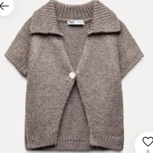 Beige stickad väst från Zara - Snygg beige stickad väst från Zara med korta ärmar, bred krage och en knapp framtill. Perfekt att slänga över en t-shirt eller skjorta för en chill och trendig look. Mjuk och skön känsla tack vare det stickade materialet.