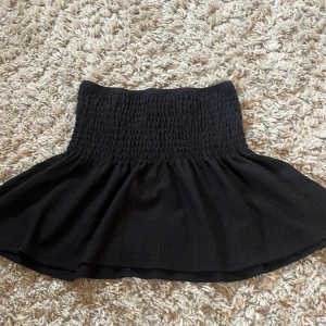 Svart kortkjol från Gina Tricot - Supersöt svart kortkjol från Gina Tricot i storlek S. Kjolen är ribbad och sitter jättefint! 