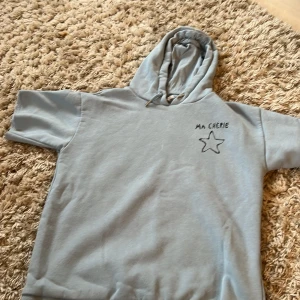 Ljusblå hoodie med tryck Ma Chérie - Avklippt hoodie som sitter perfekt. Har varit en långärmad men nu kortärmad. Mjuk och skön att ha både i skolan och hemma. 