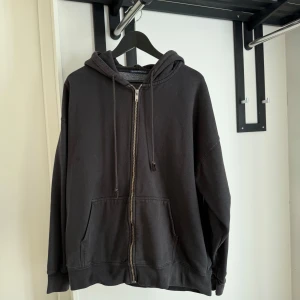Svart hoodie - Brandy Melville - Svart hoodie från Brandy Melville med dragkedja framtill och två stora fickor. Tröjan har huva med snörning och är långärmad. 