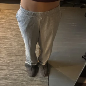 Grå mjukisbyxor med resårmidja - Säljer ett par grå mjukisbyxor med resår i midjan och raka ben. Byxorna har en avslappnad passform och sidofickor, perfekta för chill dagar hemma eller när du vill vara bekväm. Materialet är mjukt och skönt mot huden. Orginelt resor i botten, men har klippt av de.