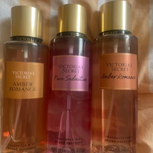 Victoria's Secret body mists 3-pack - Tre fräscha body mists från Victoria's Secret: två Amber Romance med guldig etikett och en Pure Seduction med rosa etikett. Flaskorna är genomskinliga med guldfärgade lock och rymmer 250 ml vardera. Perfekt för dig som älskar söta och fruktiga dofter.