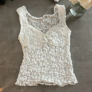Vit spetslinne från Nelly med knyt - Supersöt vit ärmlös spets topp från Nelly. Använt bara en gång! 