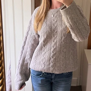 Beigegrå kabelstickad tröja från Ellos - Mysig beige kabelstickad tröja från Ellos med rund halsringning och långa ärmar. Tröjan har en loosefit och är perfekt till hösten & vintern🫶🤍 obs lite nopprig men inget man tänker på så mycket 