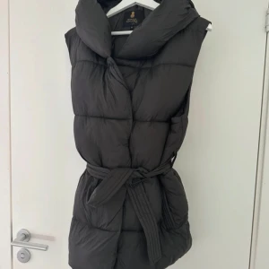 dunväst med bälte - Snygg dunväst med ett praktiskt bälte i midjan.