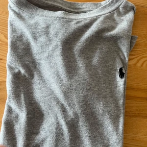 Grå långärmad tröja från Polo Ralph Lauren - Säljer en stilren grå långärmad tröja från Polo Ralph Lauren. Tröjan har en klassisk design med en liten broderad logotyp på bröstet. Perfekt för en avslappnad och snygg look.