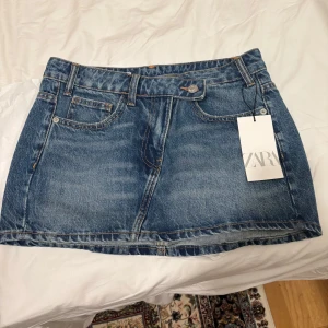 Jeanskjol från Zara - Snygg jeanskjol från Zara i klassisk blå denim. Kjolen har en kort längd och är försedd med bälteshällor och en knapp framtill. Perfekt för en avslappnad stil.Skriv innan köp💓