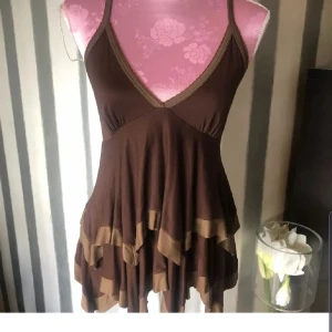 Brun linne från Zara - Säljer en brun topp  från Zara med volangdetaljer och v-ringad design. Klänningen har smala axelband och en flödande passform som ger en avslappnad look.