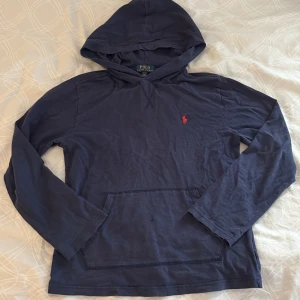 Mörkblå hoodie från Polo Ralph Lauren - Säljer en snygg mörkblå hoodie från Polo Ralph Lauren med det klassiska röda broderade logotypen på bröstet. 10-12 år 