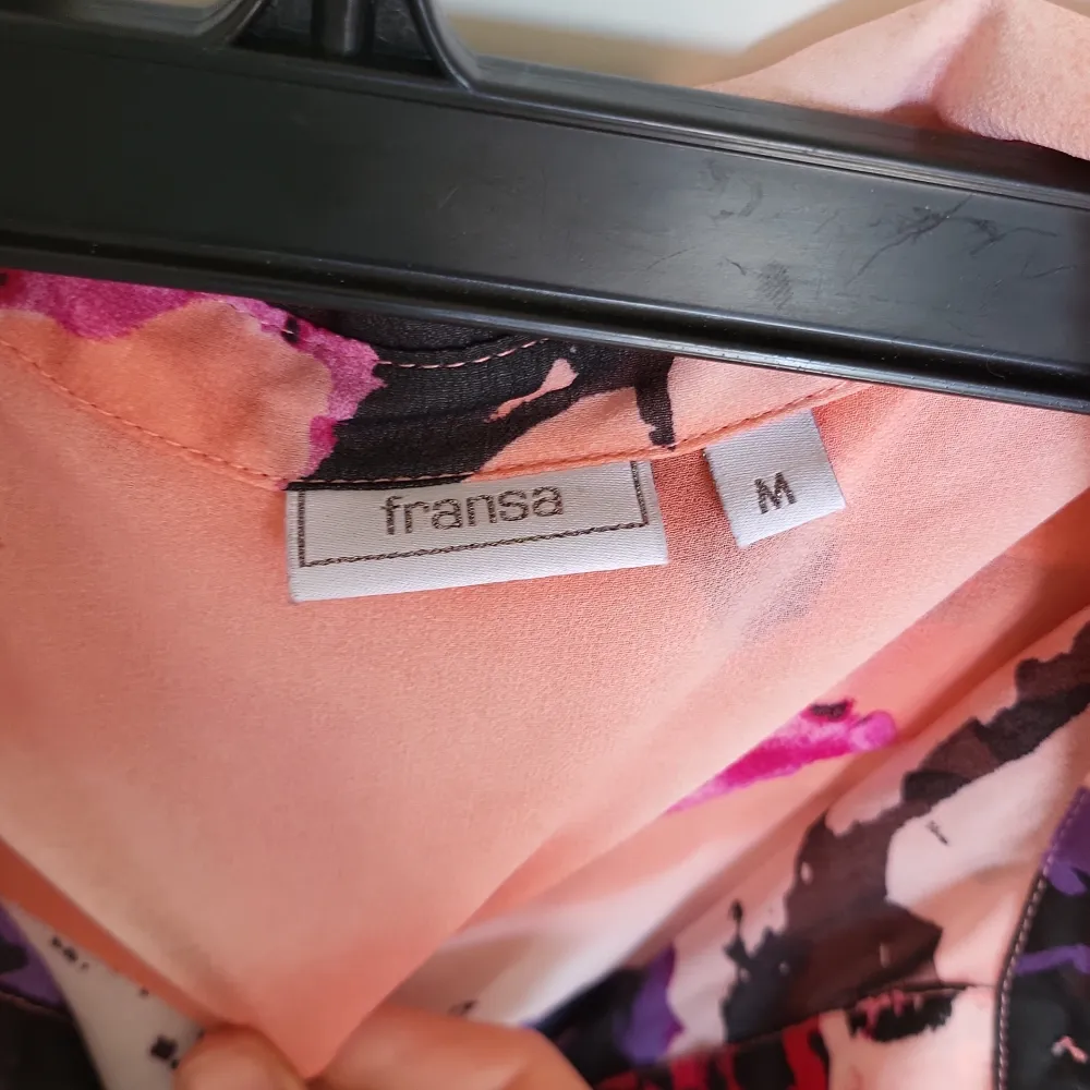 Säljer en färgglad blommig blus från Fransa i storlek M. Blusen har långa ärmar och ett vackert mönster i rosa, lila och svart. Perfekt för att liva upp garderoben!. Paidat.