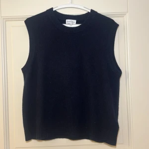 Svart stickad väst från Davida - Snygg svart stickad väst från Davida i storlek M. Perfekt för lager-på-lager-stil med ribbad halsringning och ärmkanter. En stilren och mångsidig väst för alla tillfällen.