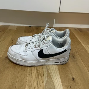 Vita Nike Air Force  - Säljer ett par vita Nike Air Force sneakers med svart swoosh. Storlek 43 kontakta vid fler frågor