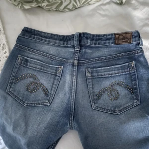 Blå jeans med slitningar - Snygga blå jeans med coola slitningar framtill och dekorativa nitar på bakfickorna. Märket är mavi jeans tror jag. Storlek 29/32 