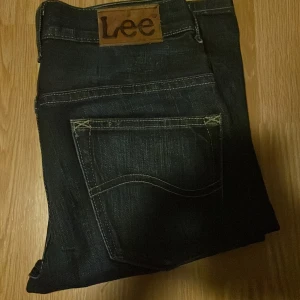 Mörkblå jeans från Lee - Snygga mörkblå jeans från Lee med klassisk femficksdesign och en bekväm passform. Perfekta för en avslappnad stil. Märkeslogga på baksidan av midjan.