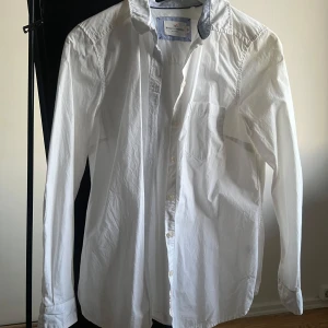 Vit skjorta från Holly & Whyte - Säljer en klassisk vit skjorta från Holly & Whyte by Lindex. Skjortan har långa ärmar och knappar framtill. Perfekt för en stilren look. Passar till många olika tillfällen.
