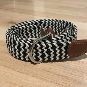 Svartvitt flätat bälte  - Tja, säljer ett snyggt svartvitt flätat bälte. Bältet är 110 cm på längden. Kan gå ner i pris vid snabb affär!